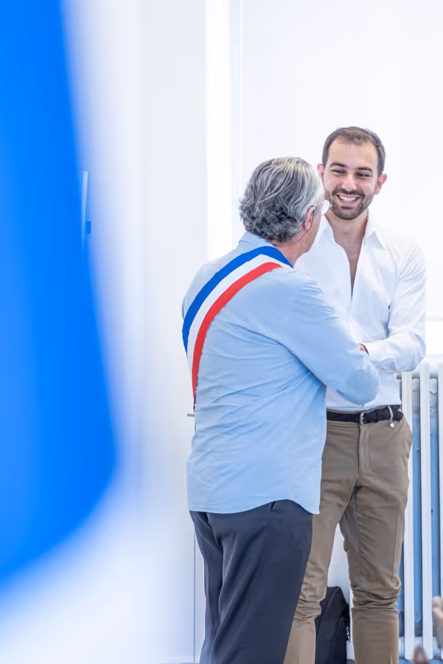 Marié souriant lors de la cérémonie civile avec le maire portant l'écharpe tricolore