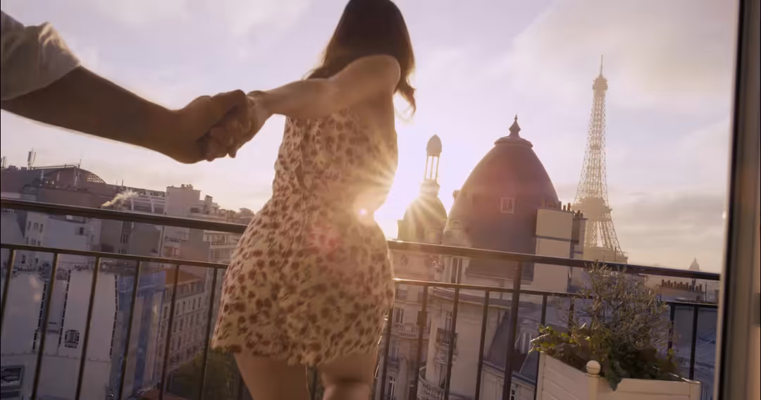 Couple holding hands on a Paris balcony at sunset, Eiffel Tower in the golden distance