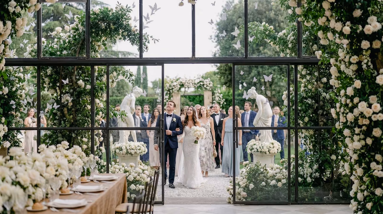 Bride and groom walking down a flower-lined outdoor aisle in the south of France