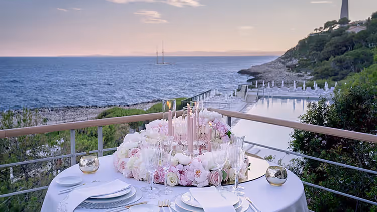 Long table set on a terrace facing the Mediterranean at sunset