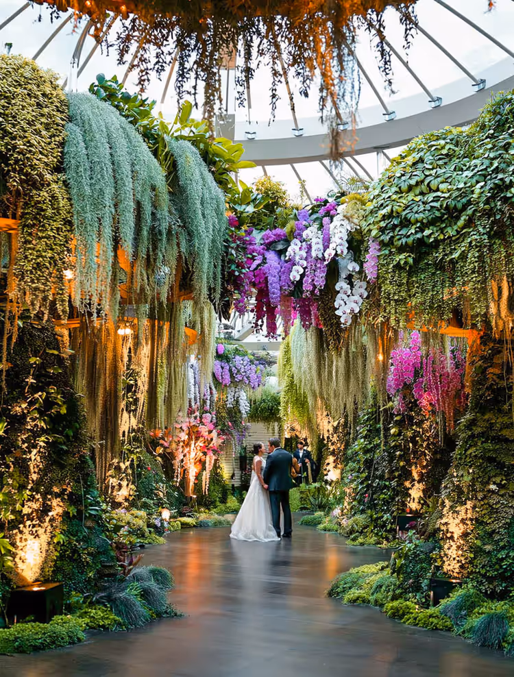 Couple enlacé sous un tunnel floral dans une serre en verre
