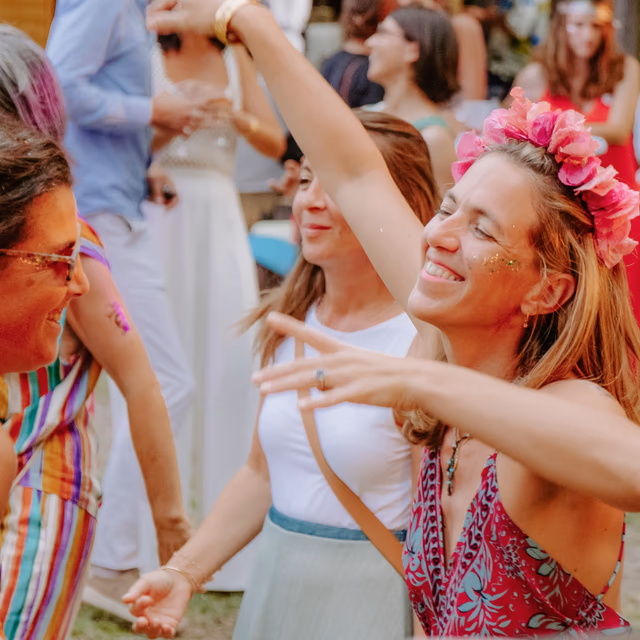 Invités dansant avec couronnes de fleurs et paillettes lors d'un mariage festival privé en Provence