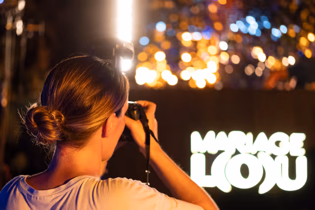 Photographe capturant une célébration de mariage sous les lumières néon et bokeh