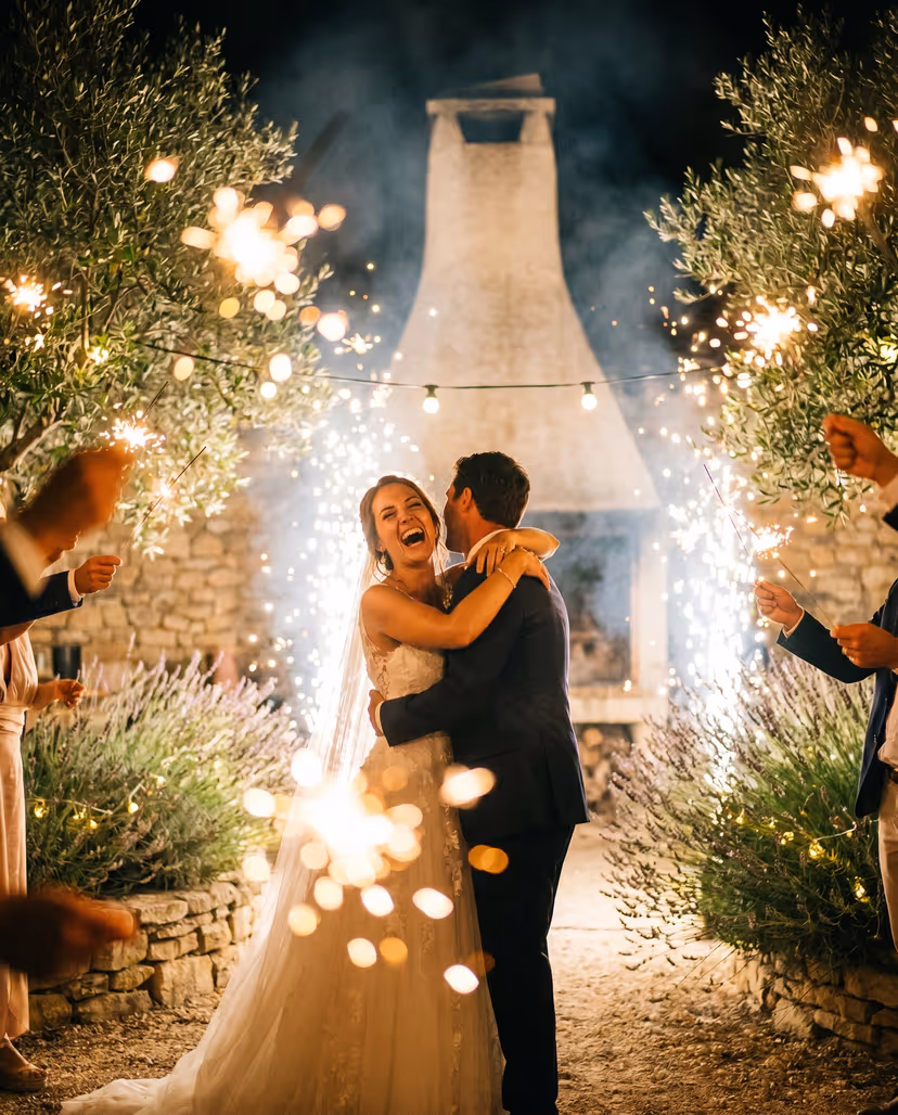 Bride and groom embracing among sparklers and olive trees at night in Provence